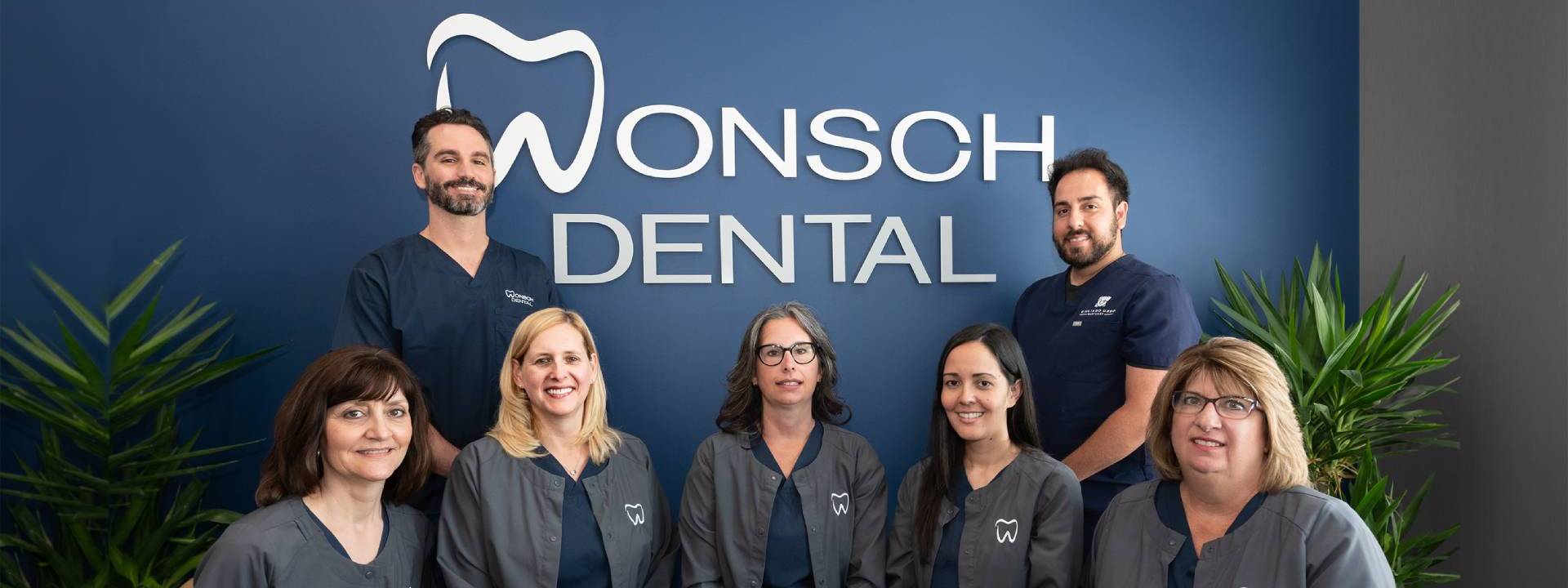 A group of people standing in front of a sign that says wonsch dental.